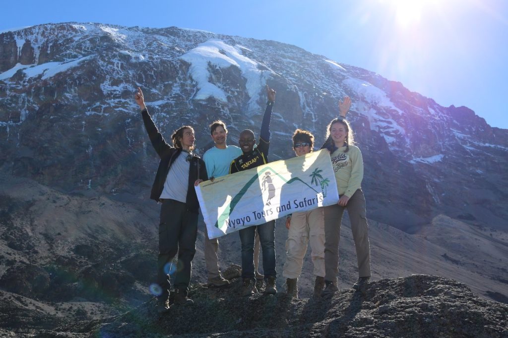 Tourists on top of Mount Kilimanjaro with Nyayo tour guide